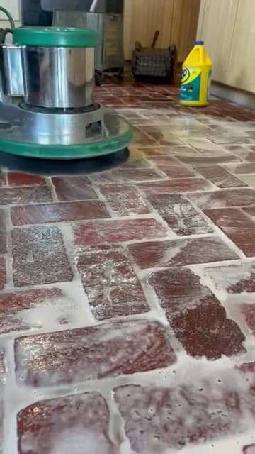Rotary floor buffer scrubbing a tile floor during a deep clean